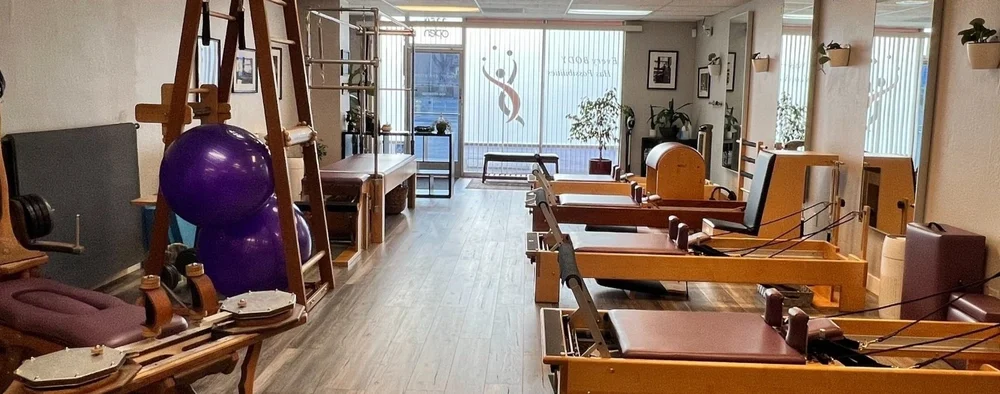 The front room of the studio: reformers, a GYROTONIC tower, and the sign in the window